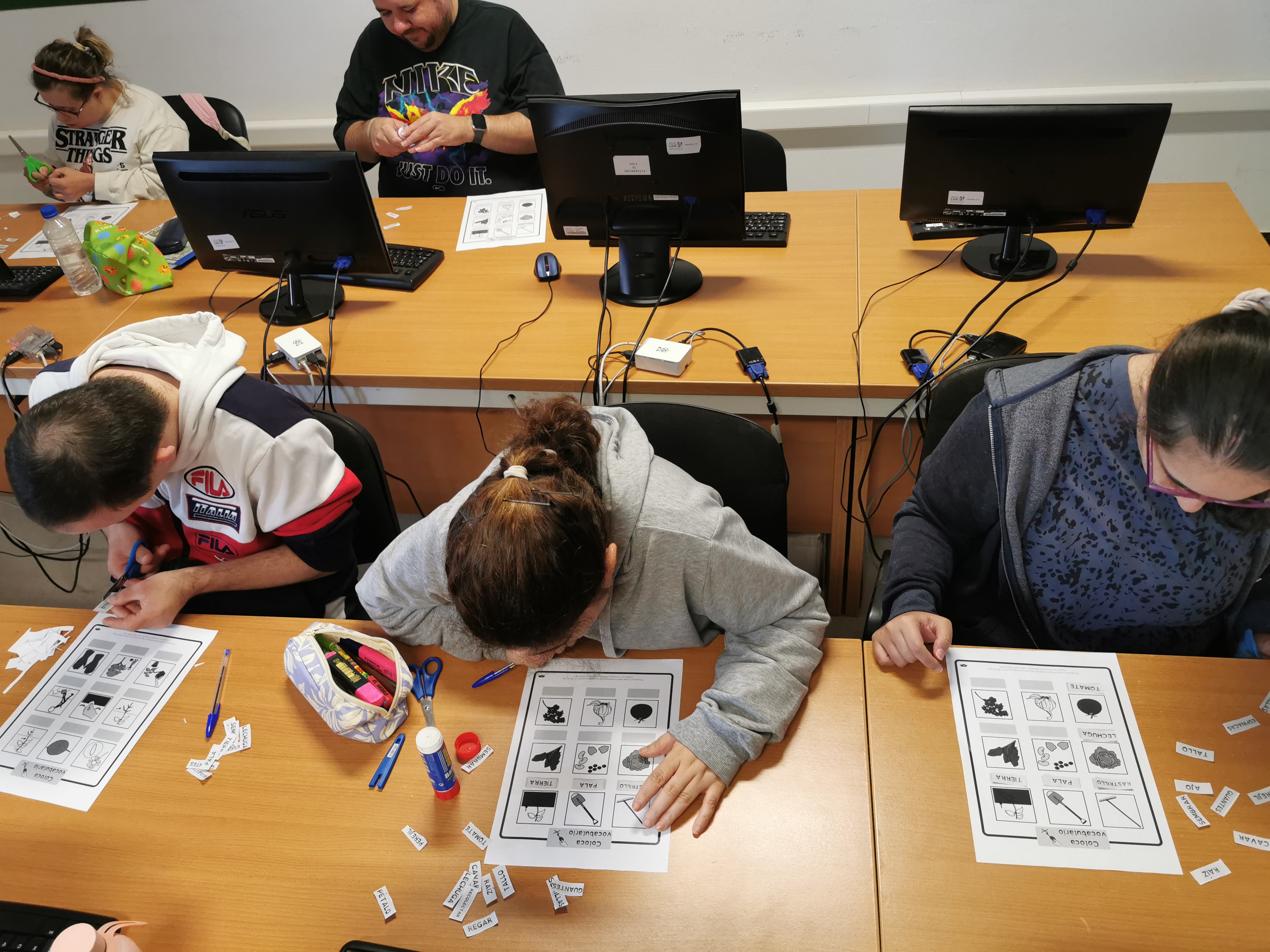 Las personas participantes del proyecto están sentadas en un escritorio y trabajan en una actividad con pictogramas.